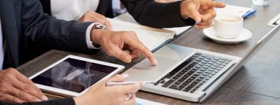 Crop colleagues using laptop at table Faceless shot of formal businesspeople using laptop at table and discussing new project