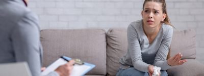 Psychological help service. Depressed female patient having psychotherapy session with counselor at office. Young woman with emotional or family problems consulting mental health professional